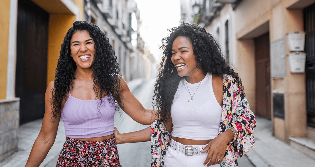 Two friends holding arms, walking in a new city together.