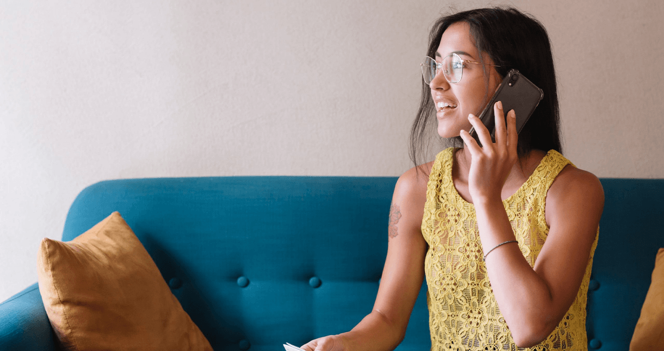 Woman sitting on the sofa, speaking on the phone.